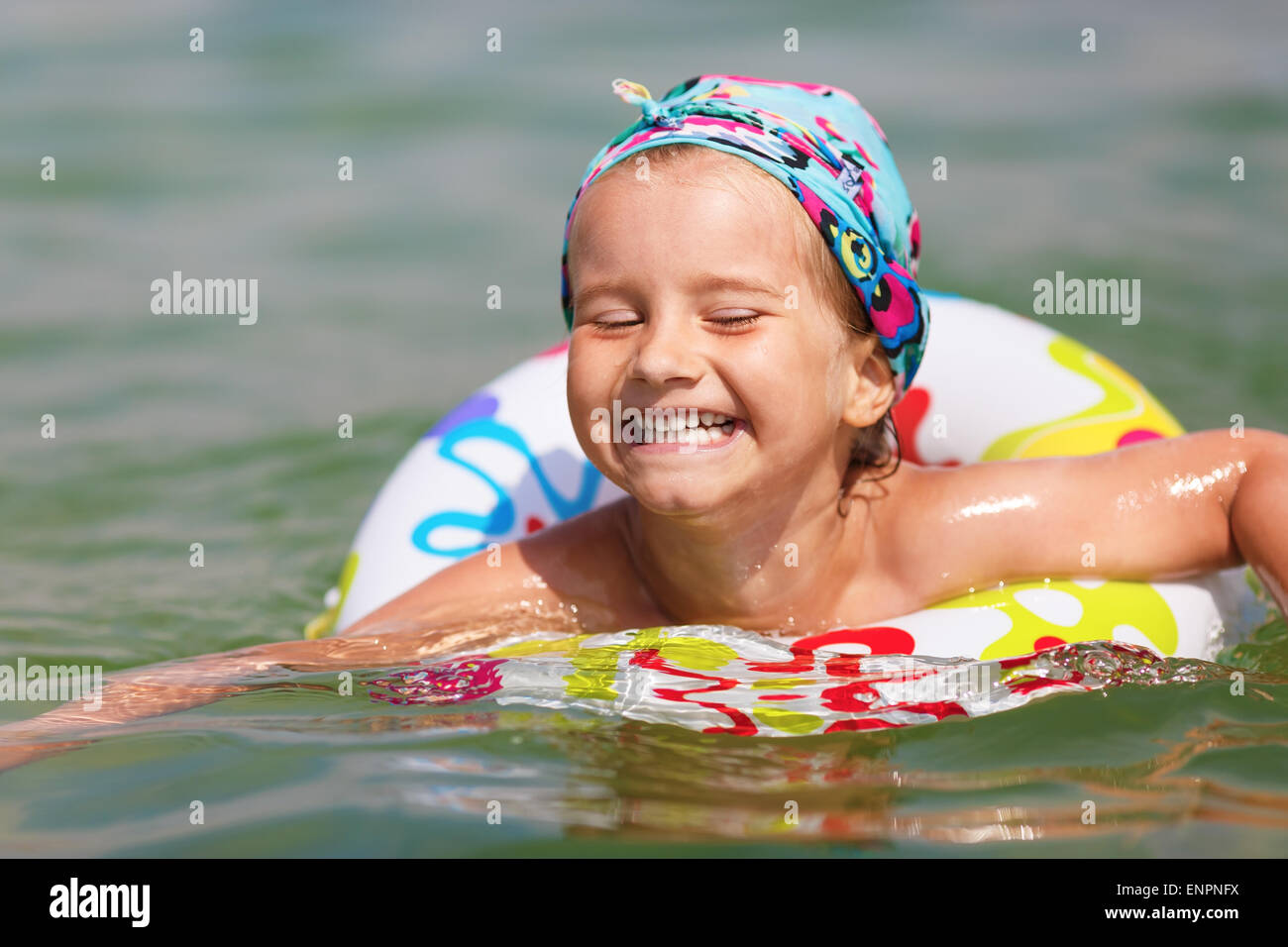Glückliches Kind schwimmt im Meer auf aufblasbaren Ring an einem klaren sonnigen Tag. Geringe Schärfentiefe. Konzentrieren Sie sich auf das Modell Gesicht. Stockfoto