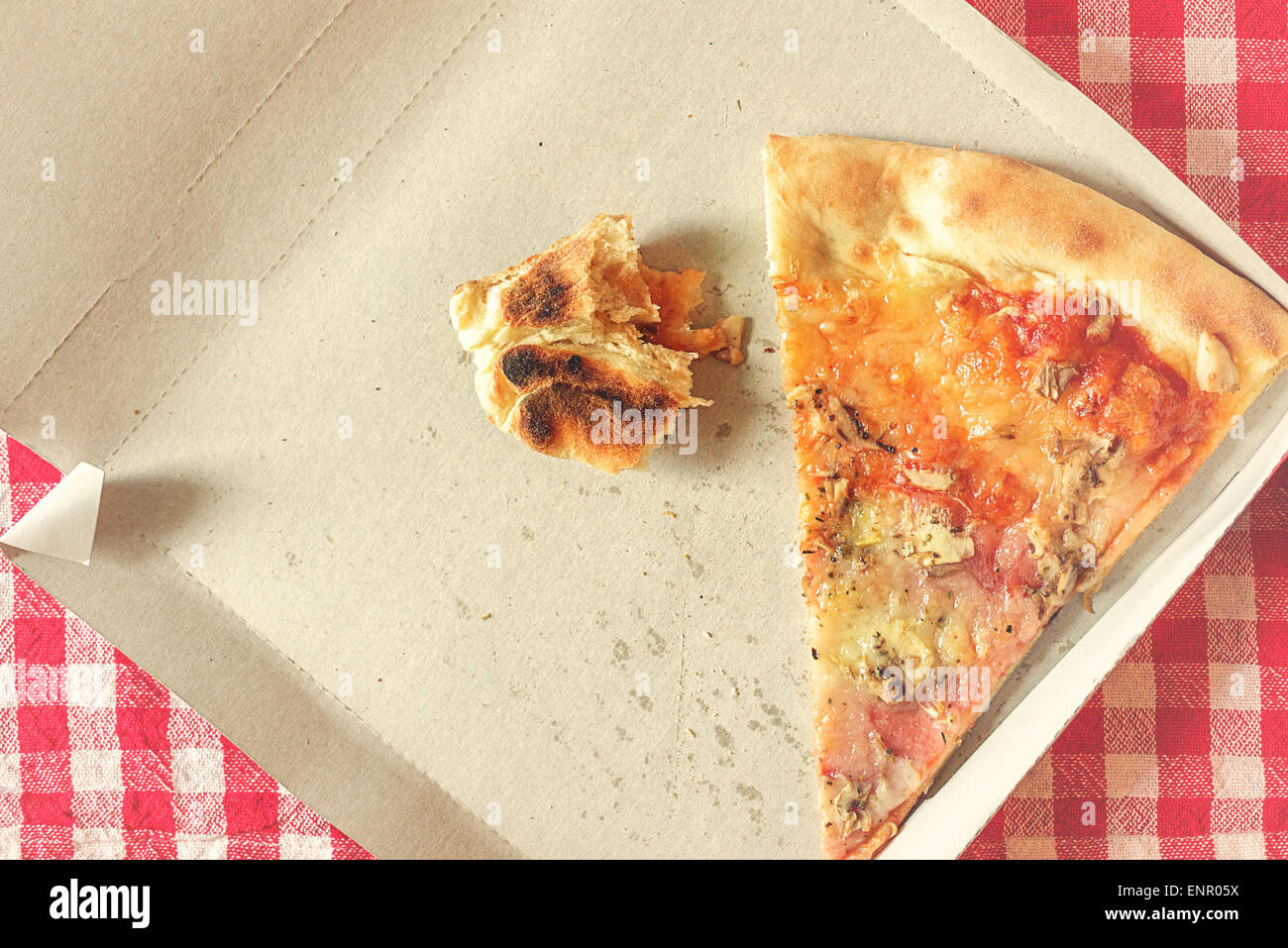 Pizzastück und Fastfood-Reste im Karton am Küchentisch, Retro-Stil getönten Bild, selektiven Fokus Stockfoto