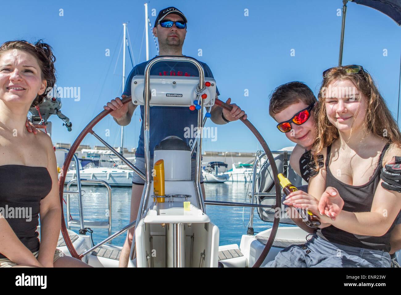 Mann, der einen Wildschwein und eine Familie um sich herum auf einer Yacht an der Bucht von Porto Colon sitzt, Reise nach Mallorka Stockfoto