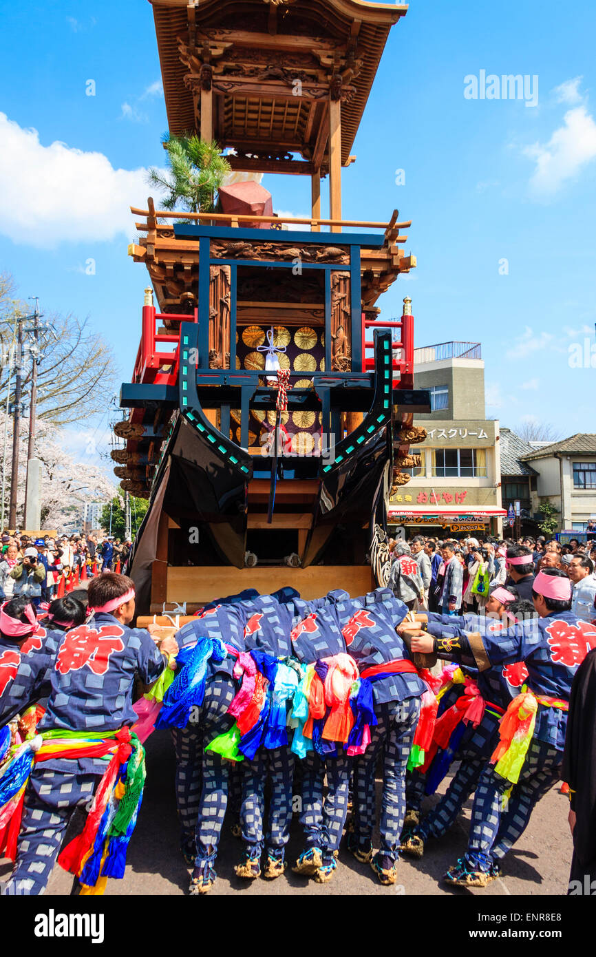 Ein Team von Männern, die sich bemühen, einen massiven Dashi, Yama, Holzwagen zu schieben, umgeben von Massen von Touristen, die das Frühlingsfest von Inuyama beobachten Stockfoto