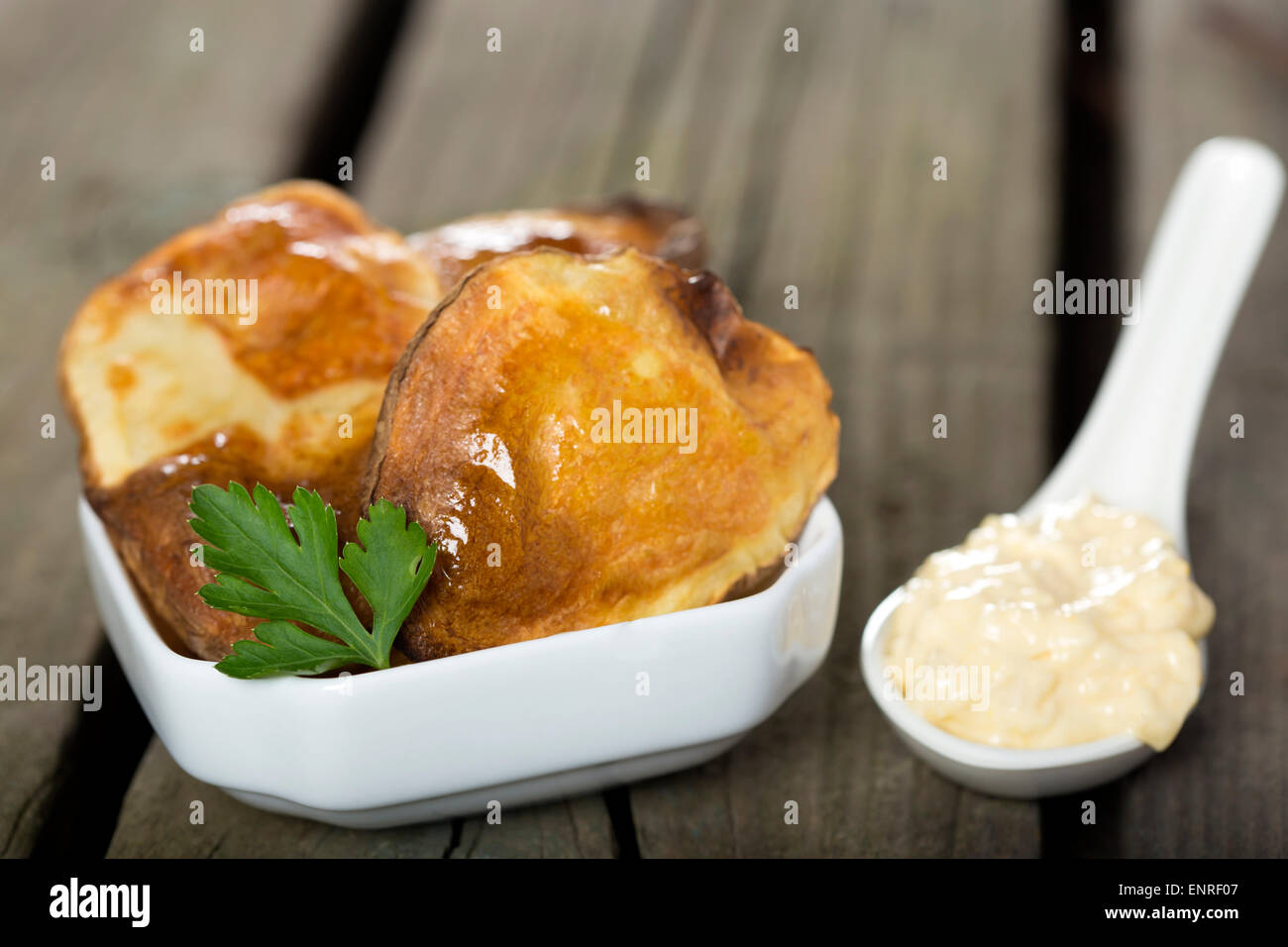 Gebackene Kartoffeln in weiße Schüssel mit Knoblauch-Sauce über rustikale Holz Hintergrund Stockfoto