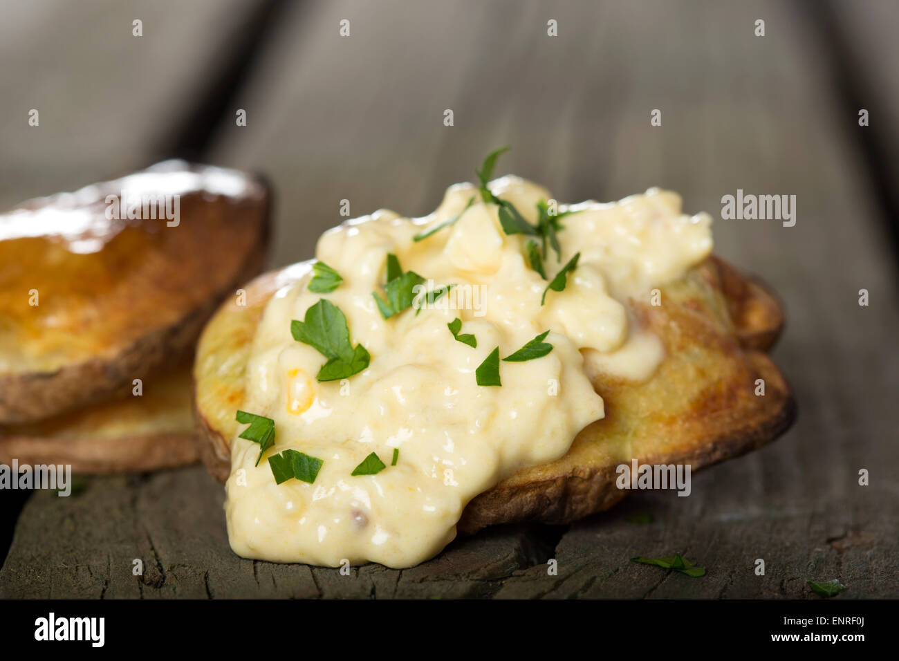 Gebackene Kartoffeln mit Knoblauch-Sauce über rustikale Holz Hintergrund Stockfoto