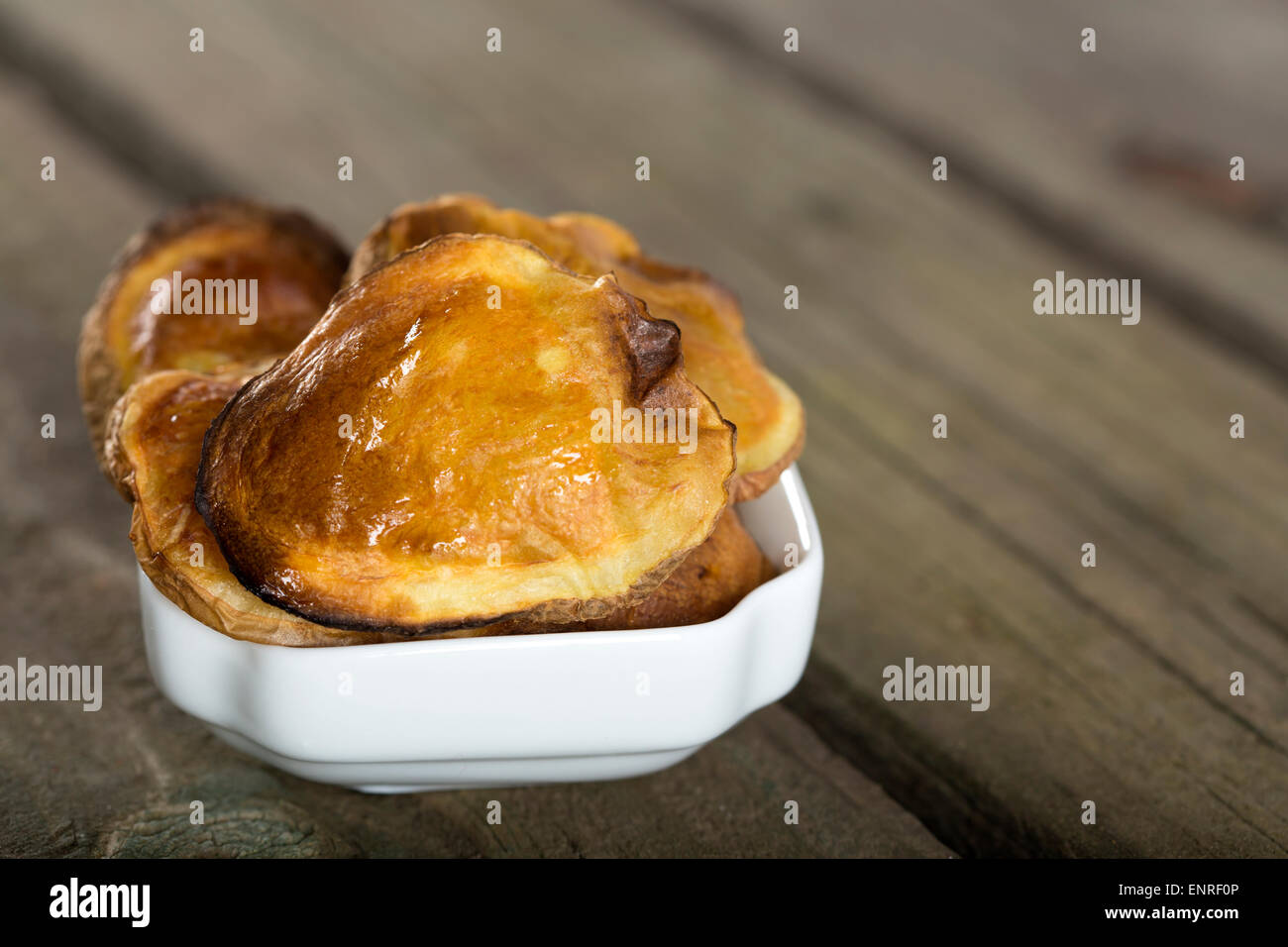 Gebackene Kartoffeln in weiße Schüssel über rustikale Holz Hintergrund Stockfoto