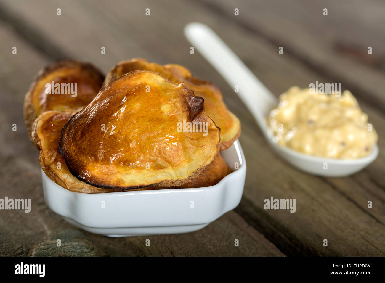 Gebackene Kartoffeln in weiße Schüssel mit Knoblauch-Sauce über rustikale Holz Hintergrund Stockfoto
