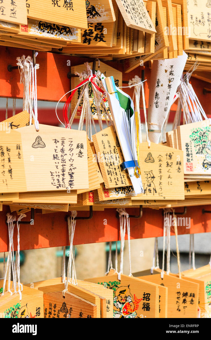 Japanische ema-Tafeln, wünschend Tabletten, hängend von Rahmen Arbeit durch rote Schnüre an einem schintoistischen Schrein. Hoffnungen, Wünsche und Widmungen sind darauf geschrieben. Stockfoto