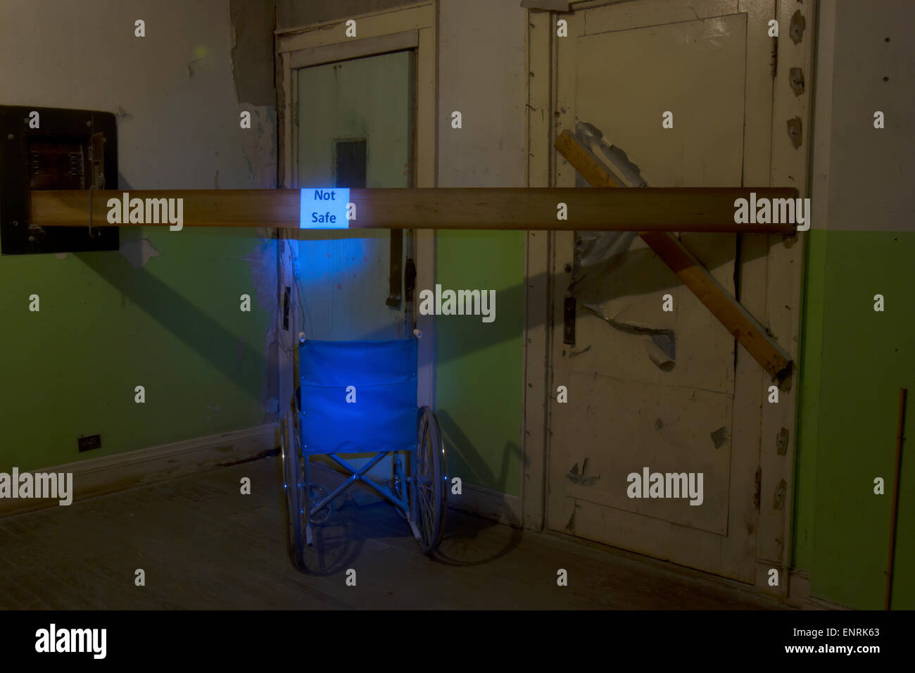 Blaue Rollstuhl mit nicht sichere Zeichen in der Ecke eines verlassenen Gebäudes. Stockfoto