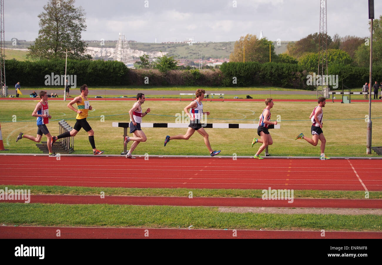 Athleten laufen in Linie, während eine Distanz auf einer Leichtathletikbahn in Portsmouth, Hampshire, England Stockfoto