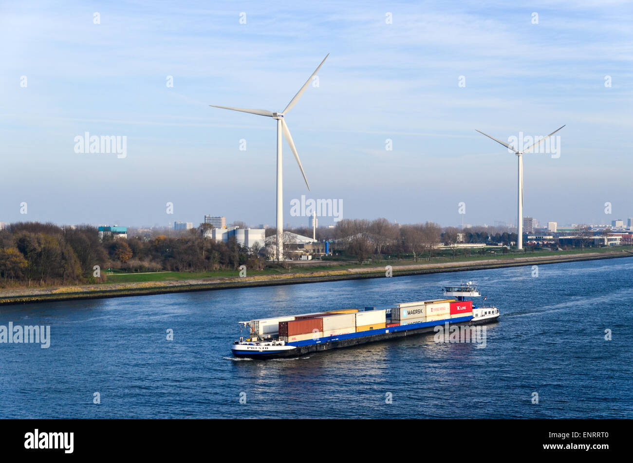 Ein Container-Schiff Segeln in den Hafen von Rotterdam, Niederlande, mit Windmühlen im Hintergrund Stockfoto