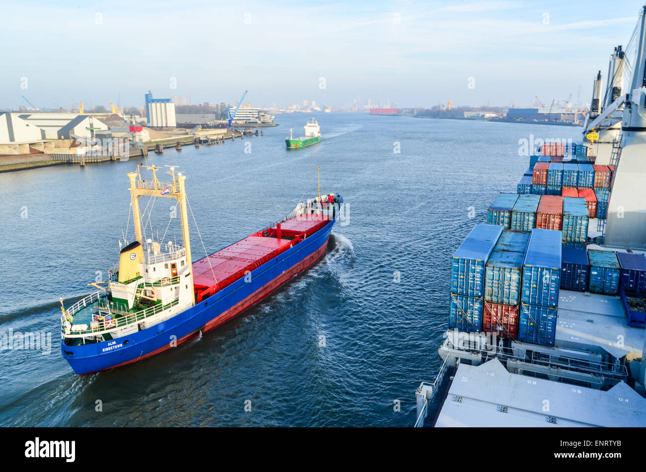 Ein Containerschiff und ein kleiner Frachter Segeln in den Hafen von Rotterdam, Niederlande Stockfoto