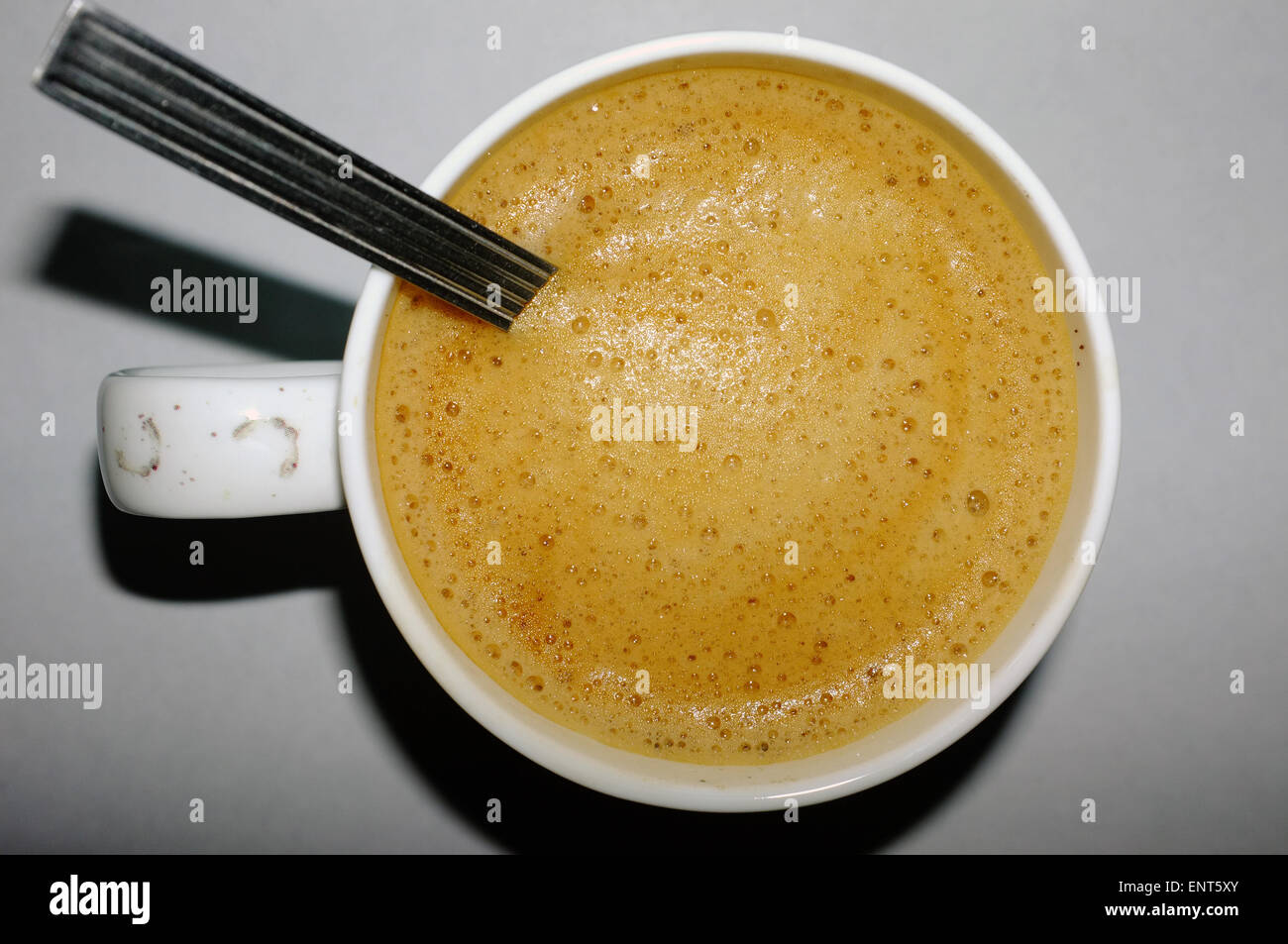 Eine Draufsicht auf eine Tasse frisch gebrühten Kaffee mit einem Teelöffel drin, Stockfoto