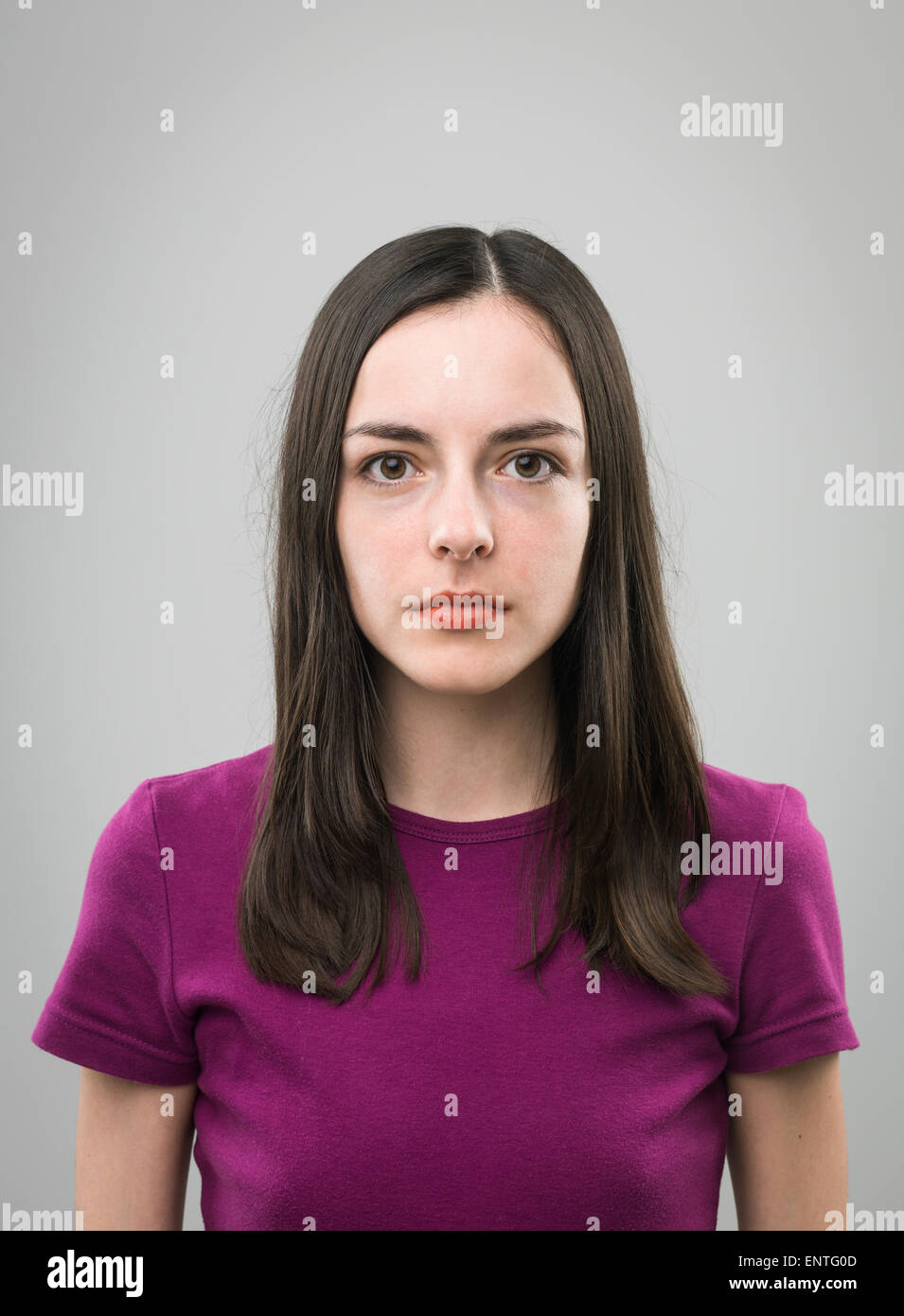 Porträt der jungen Frau mit leeren Gesichtsausdruck auf grauem Hintergrund Stockfoto