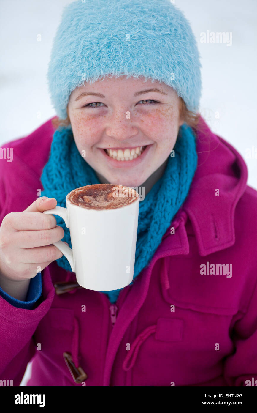 Teenager-Mädchen genießen Sie eine heiße Schokolade draußen im Schnee im Winter, UK. Stockfoto