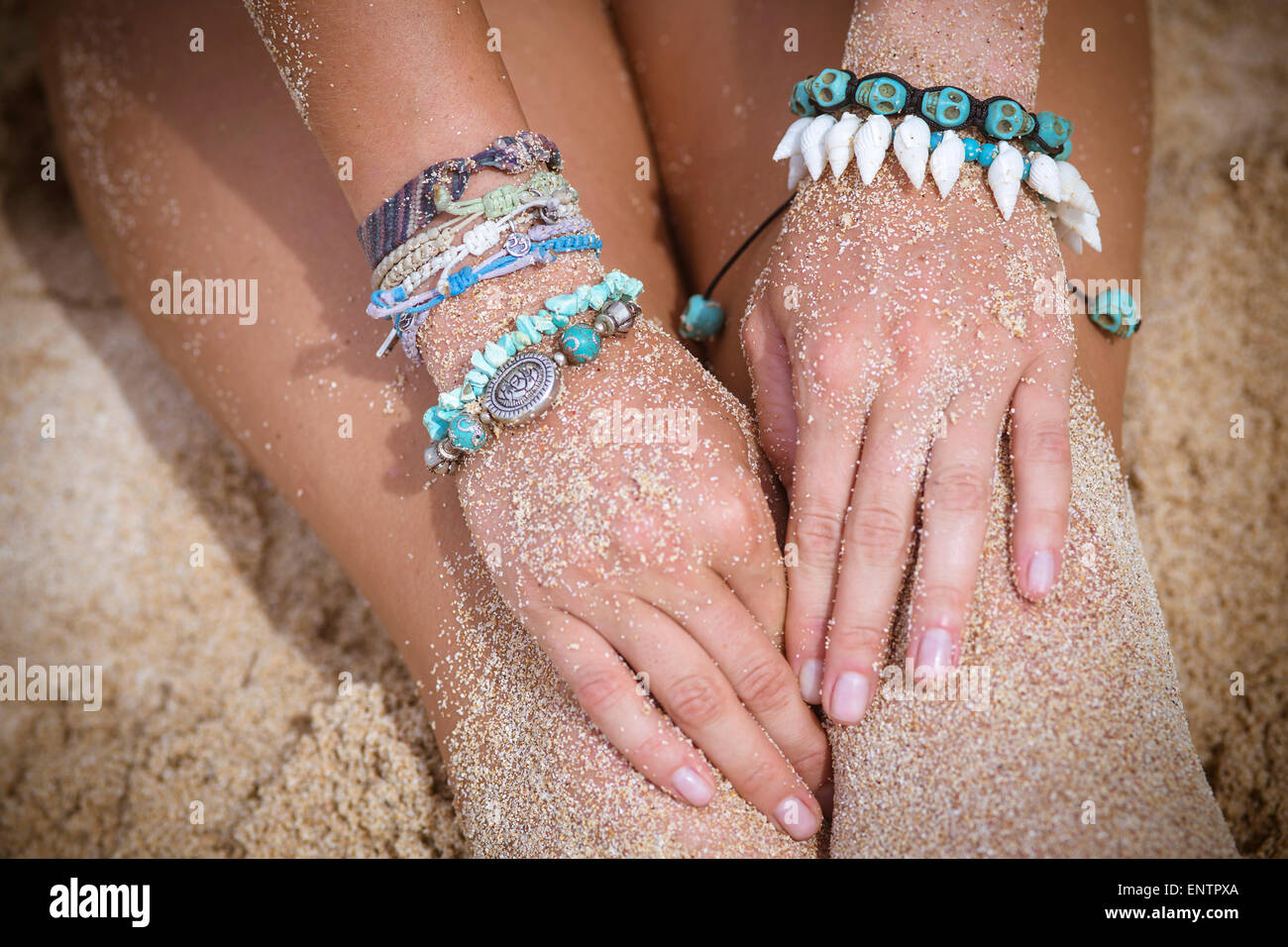 Weibliche Hand mit Armbänder am Strand. Stockfoto
