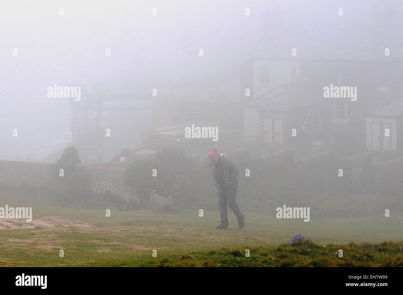 Eastbourne, East Sussex, Großbritannien. Mai 2015. Wetter in Großbritannien: Dichter Meeresnebel rollt entlang der Küste. Etwas mehr als eine Meile landeinwärts gibt es strahlende Sonneneinstrahlung.Walker mit Coastguard Cottages im Hintergrund in Birling Gap Stockfoto