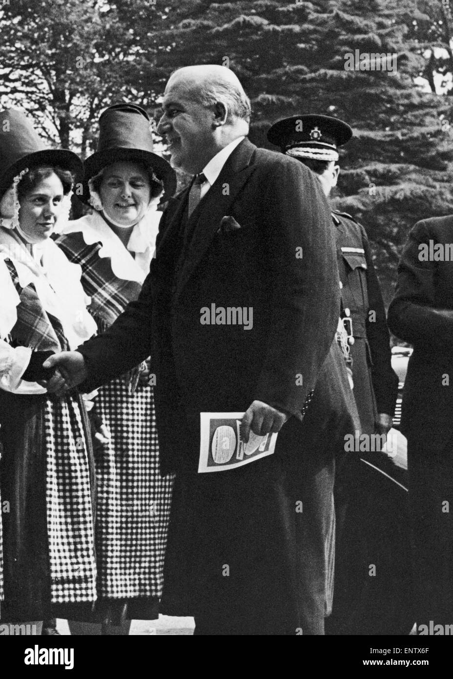 Nach Hause Sekretär David Maxwell Fyffe grüßt eine Frau in Tracht auf der walisische industrielle Messe in Cardiff. 10. September 1952. Stockfoto