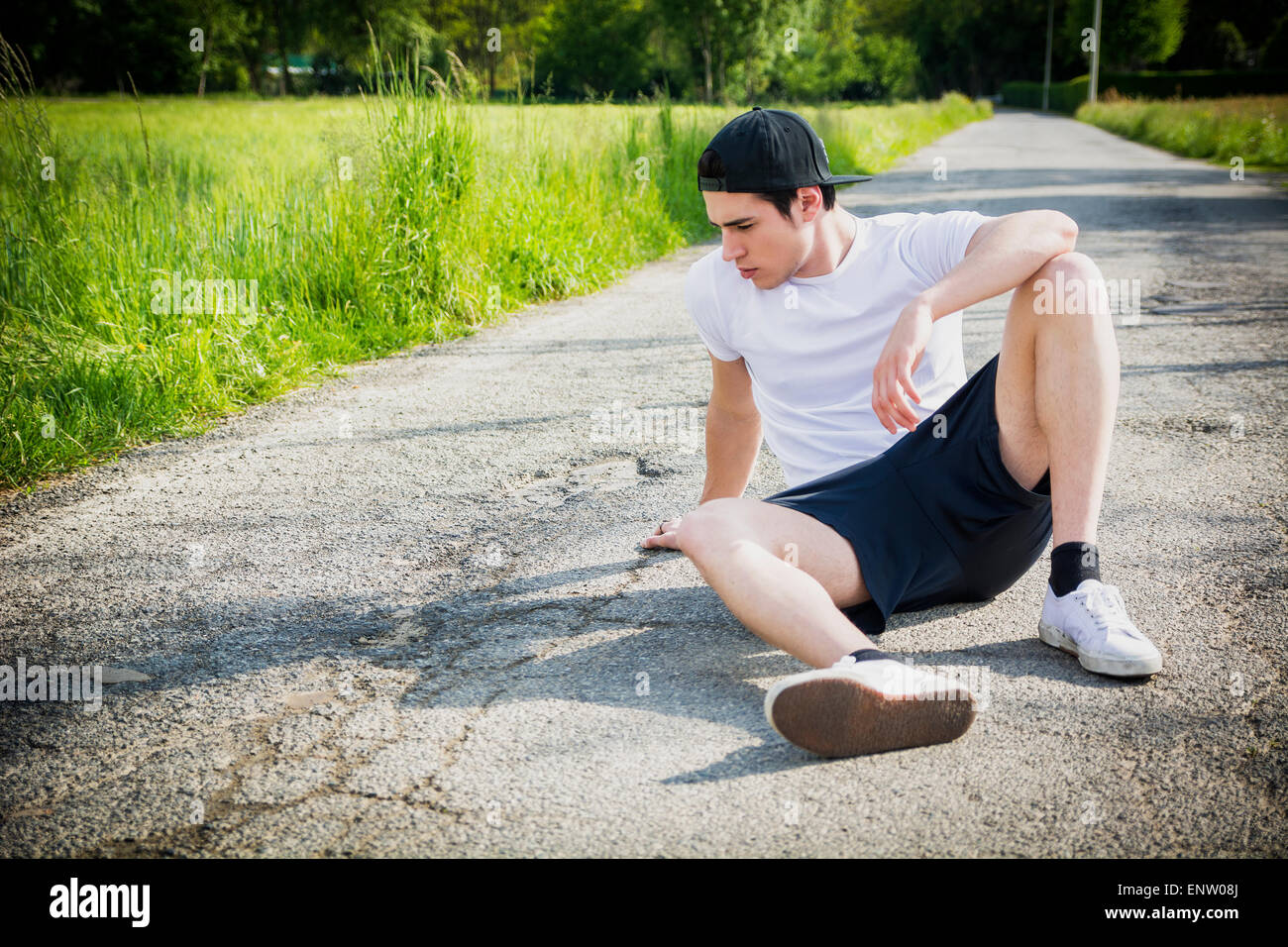 Hübscher junger Mann Ruhe sitzen auf der Straße nach laufen und Joggen im Land an einem sonnigen Tag Stockfoto