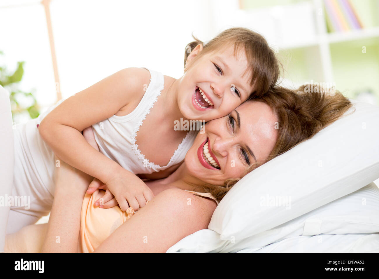 Glückliche Mutter mit Kind Tochter im Bett genießen sonnige Morgen im Hause Schlafzimmer spielen Stockfoto