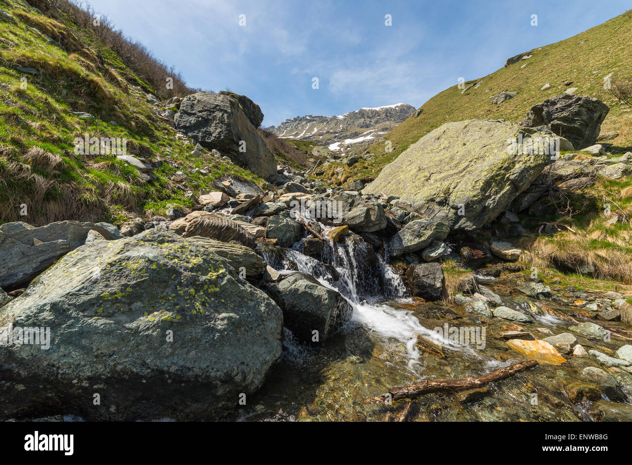 Kleinen Bergbächen aus Schmelzwasser fließt in idyllischen und unberührten Natur. Schneebedeckten Bergkette. Stockfoto
