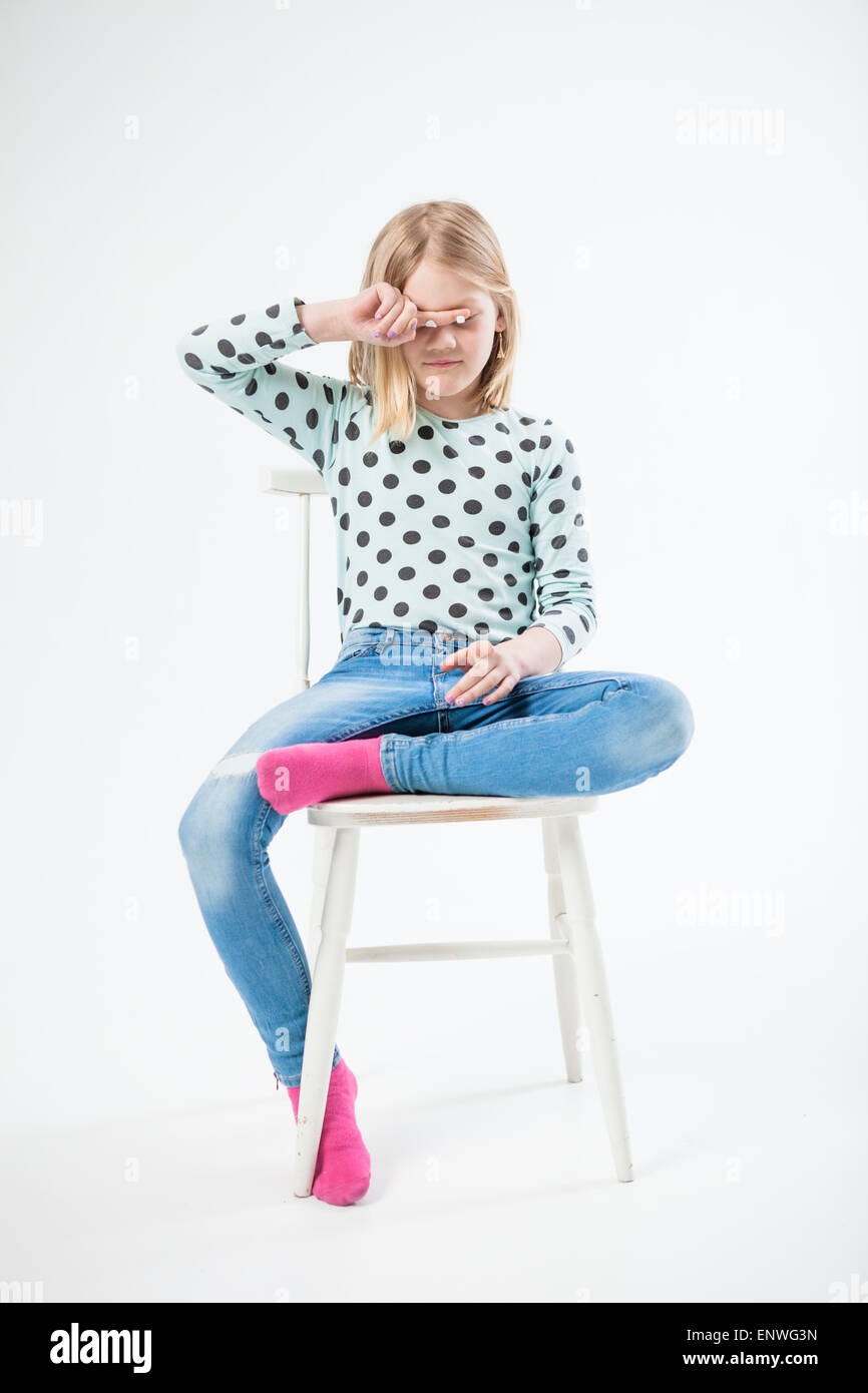 Mädchen mit Blick auf Sie und zeigen, sitzend auf einem Stuhl in einem studio Stockfoto