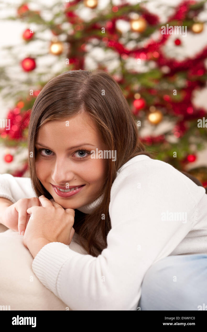 Lächelnde junge Frau vor Weihnachtsbaum Stockfoto