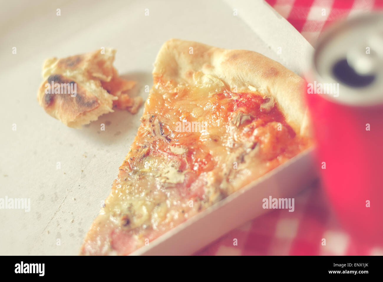 Pizzastück und Fastfood-Reste im Karton am Küchentisch, Retro-Stil getönten Bild Stockfoto