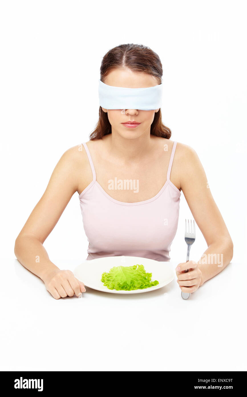 Mädchen Augenbinde sitzt vor Teller mit Salat Blatt Stockfoto