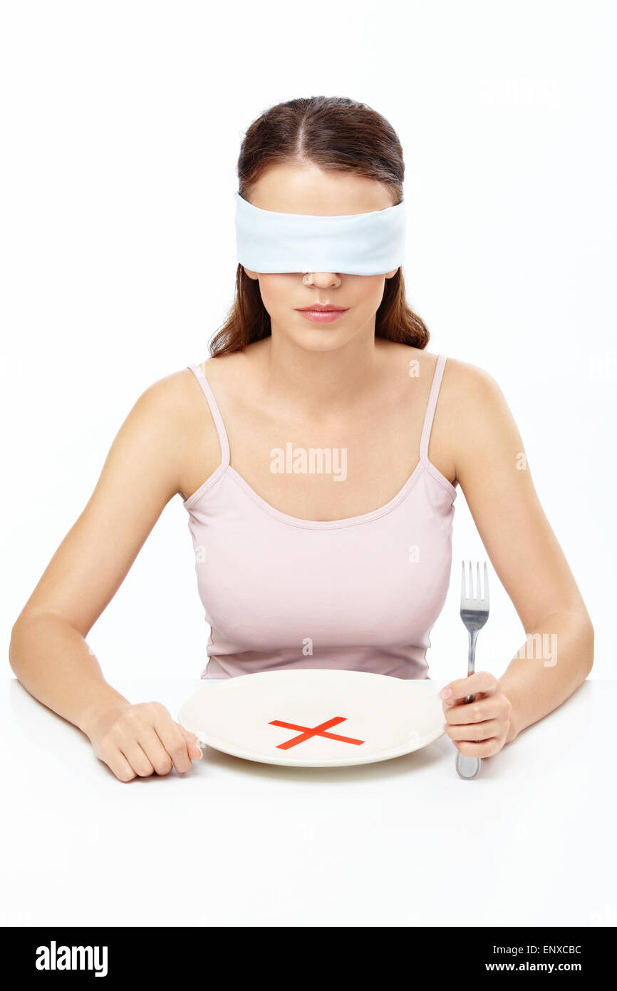Mädchen Augenbinde sitzt vor dem leeren Teller mit einem Verbot Stockfoto