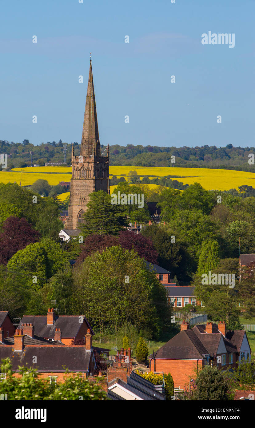 St. Johannes Kirche dominiert die Landschaft in der kleinen Stadt Bromsgrove in Worcestershire mit Feldern von Raps hinter Stockfoto