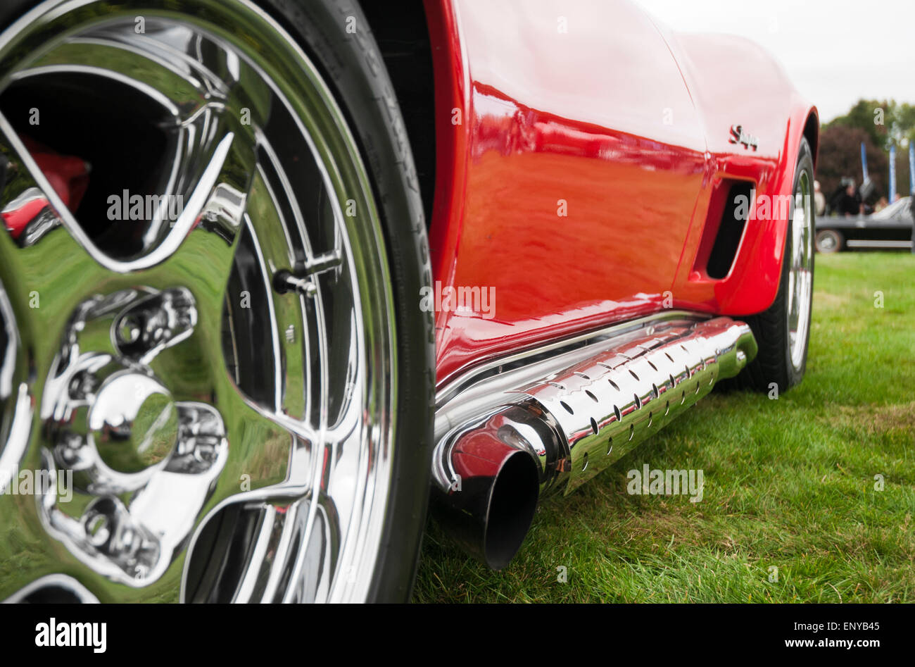 Low, close-up Blick hinunter die Seite eines roten klassischen Sportwagens, mit verchromten Details. Stockfoto