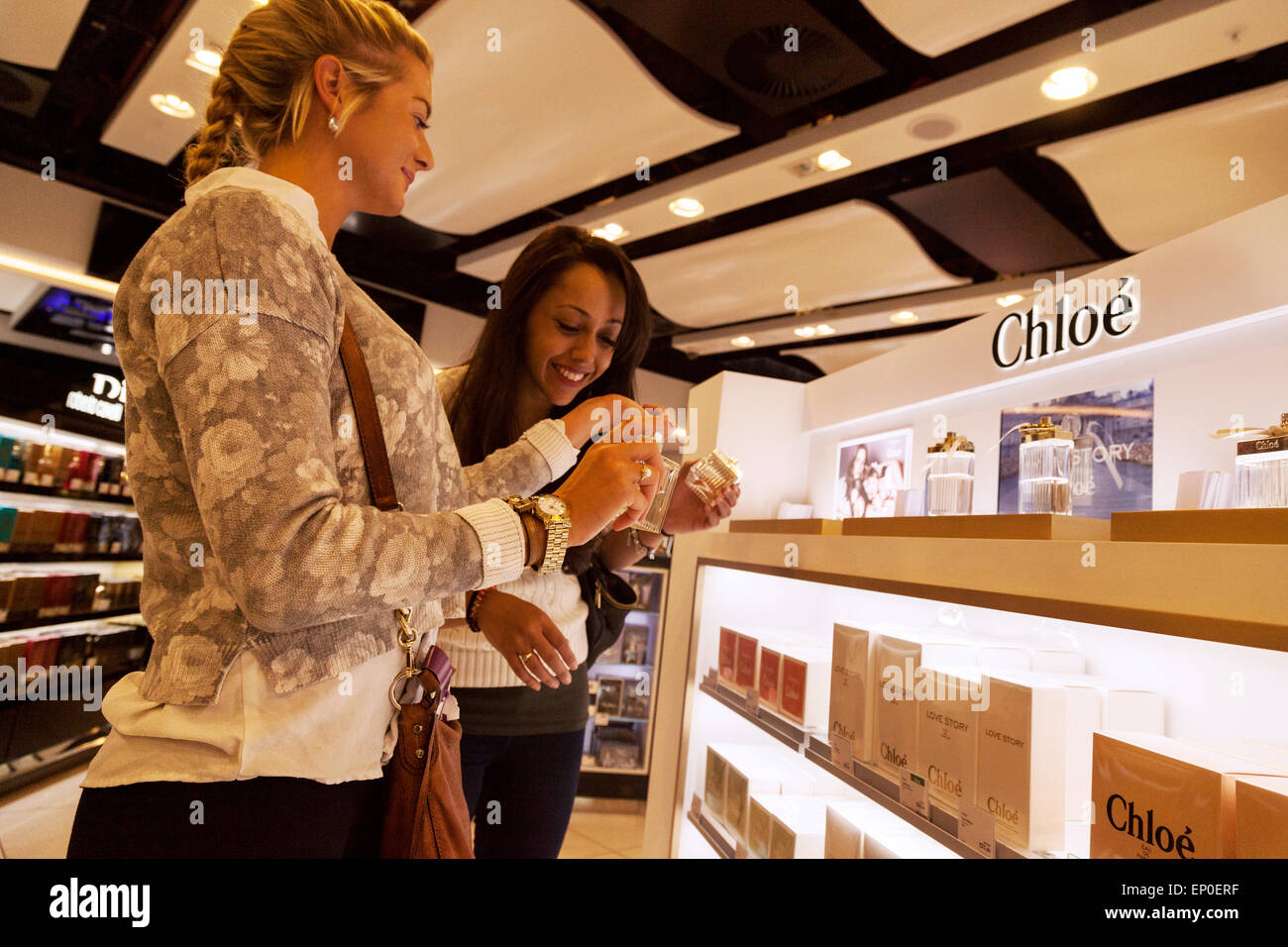 Zwei junge Frauen, die duty free shopping für Parfüm, Duty-Free-Shop, Süd-Terminal, Gatwick Flughafen London UK Stockfoto
