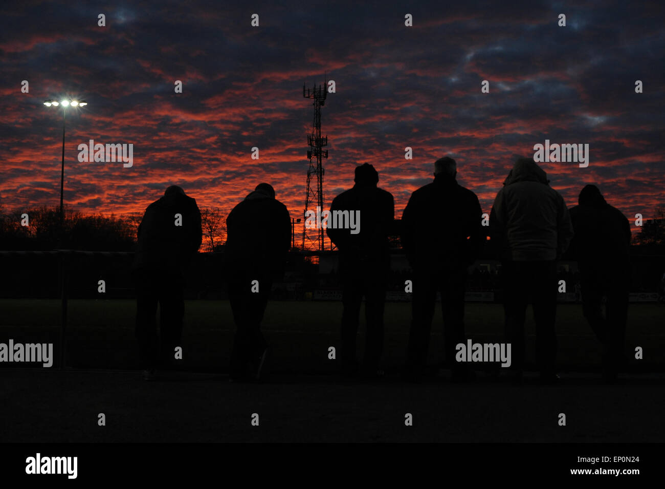 Fußball-Fans sehen ein Fußballspiel unter einem roten Sonnenuntergang, Barnsley, South Yorkshire, Großbritannien. Bild: Scott Bairstow/Alamy Stockfoto