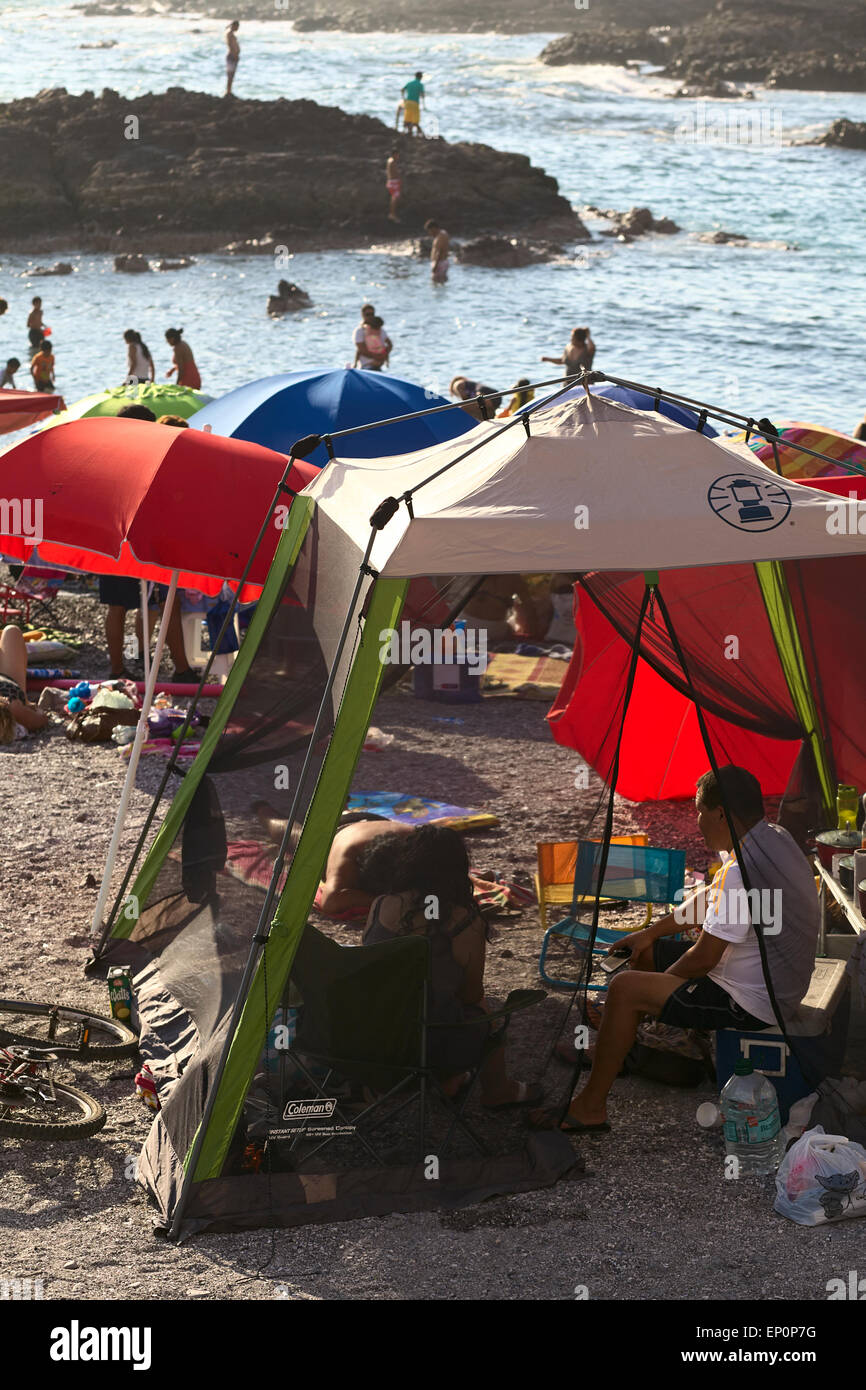 Menschen am Strand unter Sonnenschirmen und Vordächer in Iquique, Chile Stockfoto