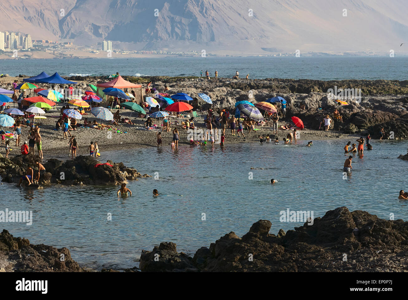 Menschen am Strand, umgeben von Felsen aus den Wellen entlang der südlichen Küste von Iquique, Chile Stockfoto