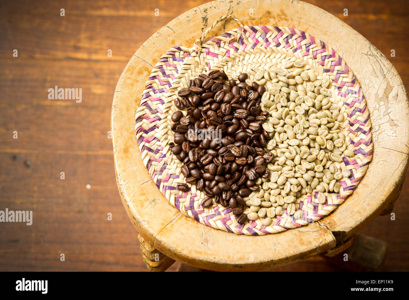 Ungerösteten Rohkaffee und dunkelbraun gerösteten Bohnen auf hölzernen Schemel. Stockfoto