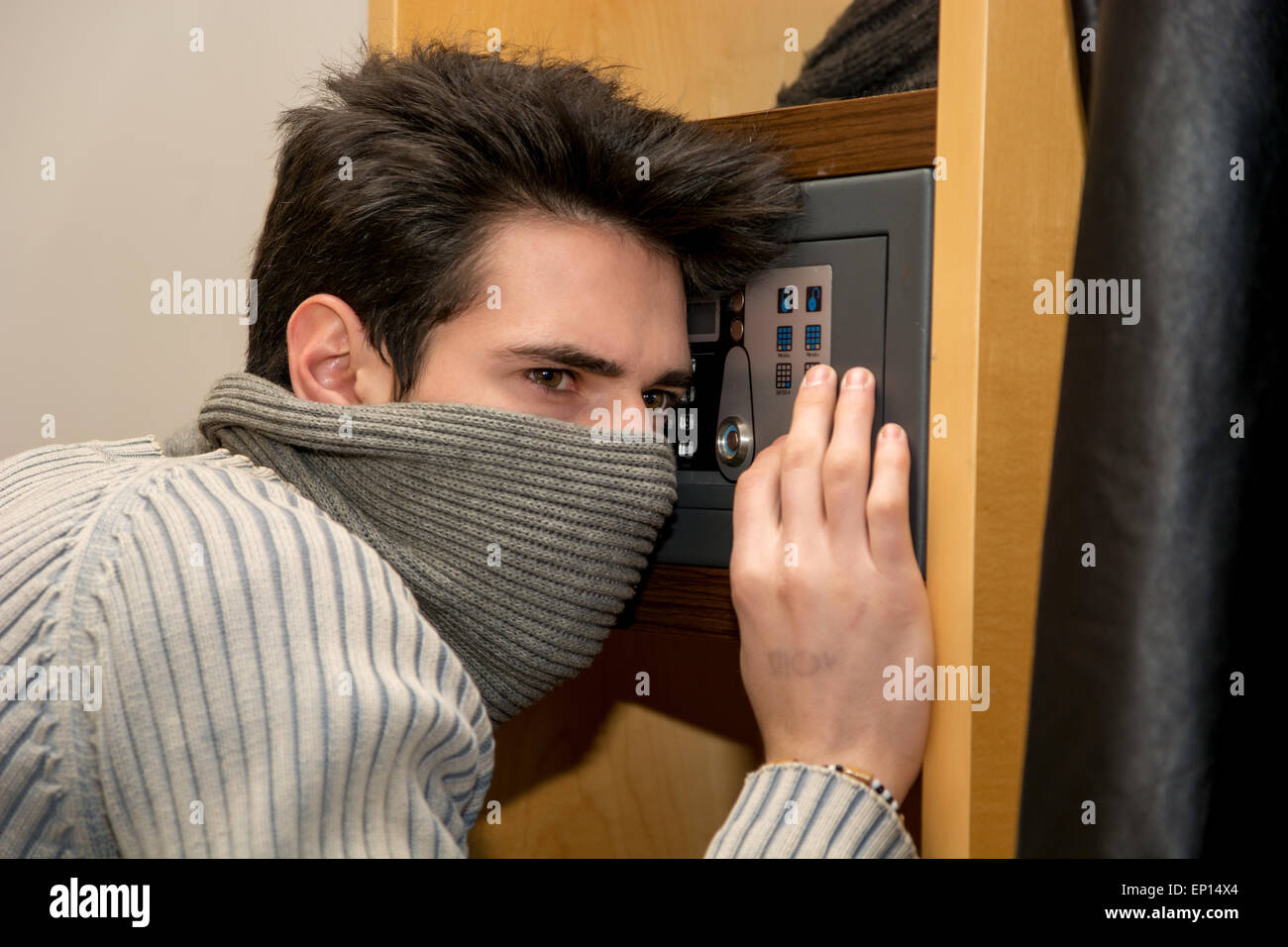 Junge männliche Einbrecher Gesicht mit Maske öffnen eine kleine Heimat Tresor oder Safe versteckt Stockfoto