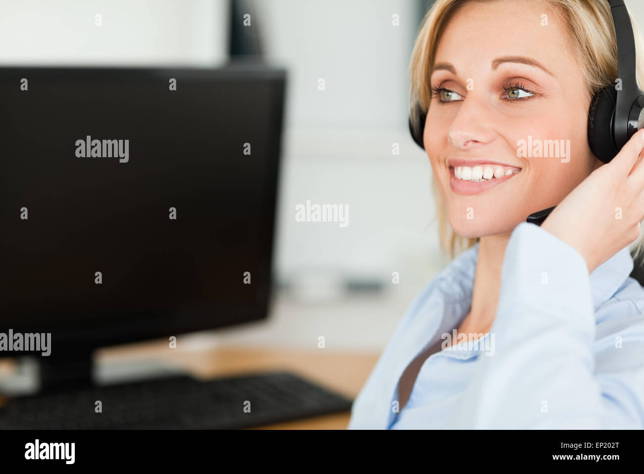 Porträt einer lächelnden Geschäftsfrau mit Kopfhörer arbeiten mit Computern, die auf der Suche an anderer Stelle Stockfoto