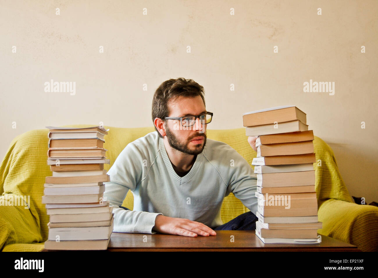 Mann, sitzend mit einem Stapel Bücher Stockfoto