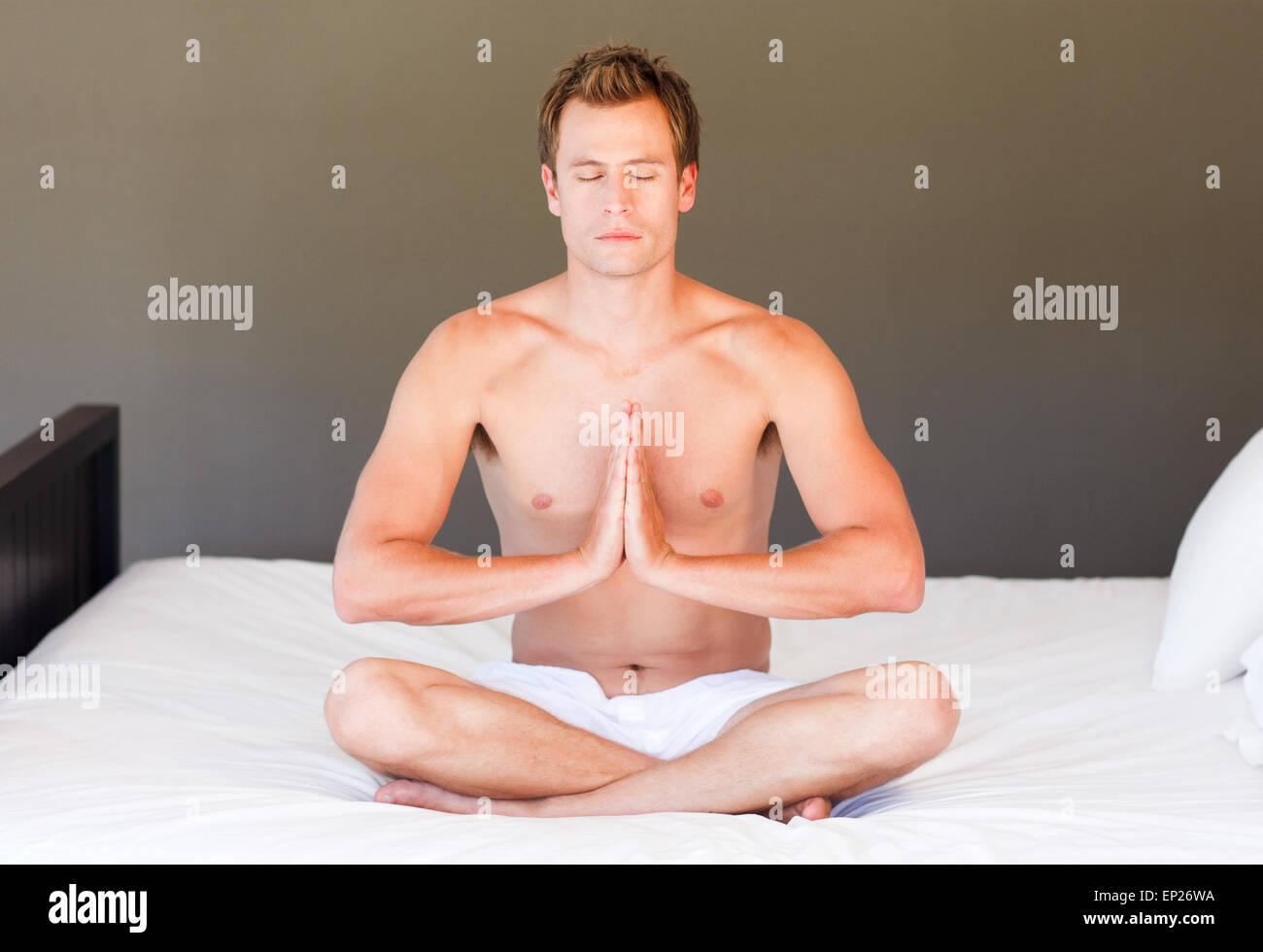 Kleiner Junge beim Yoga auf Bett mit geschlossen Augen Stockfoto