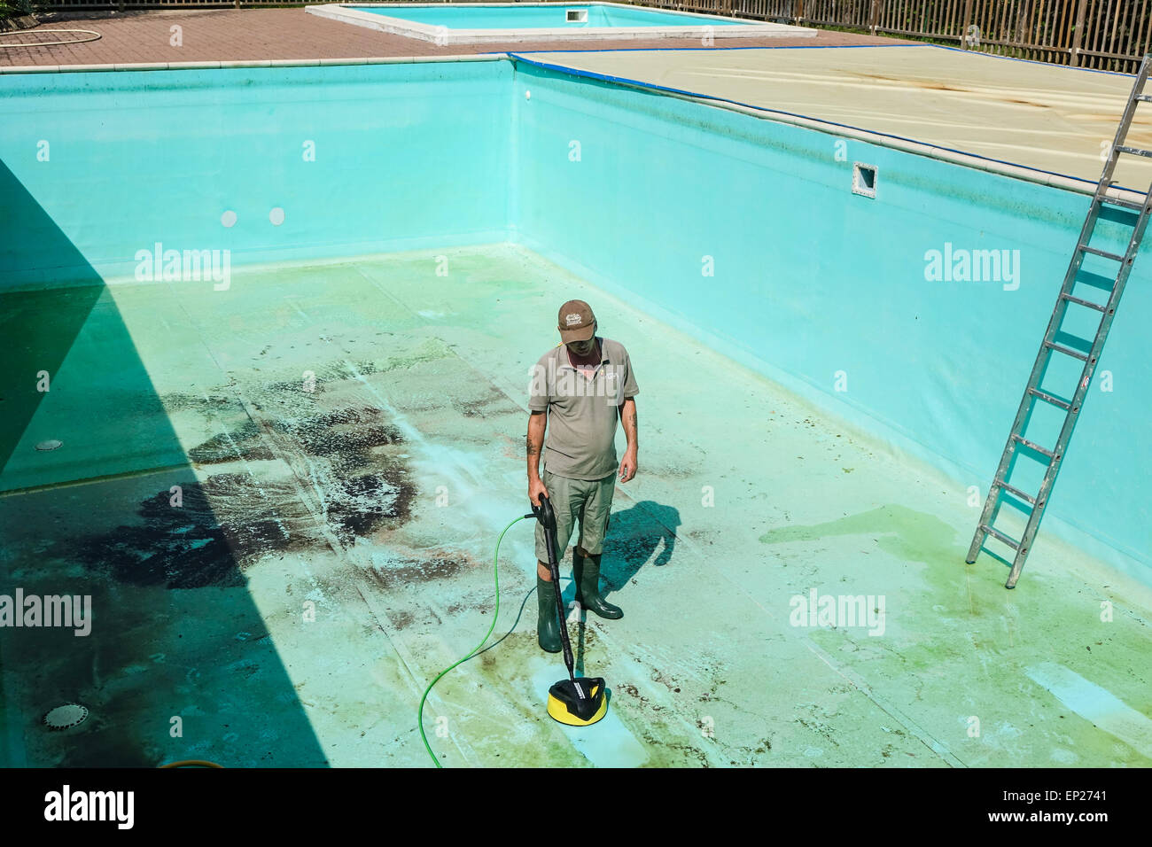 Kärcher Druck Waschmaschine macht Jet waschen Terrasse Anlage von Mann mittleren Alters in kurzen Hosen verwendet, um Schwimmbad Wände und Boden reinigen Stockfoto