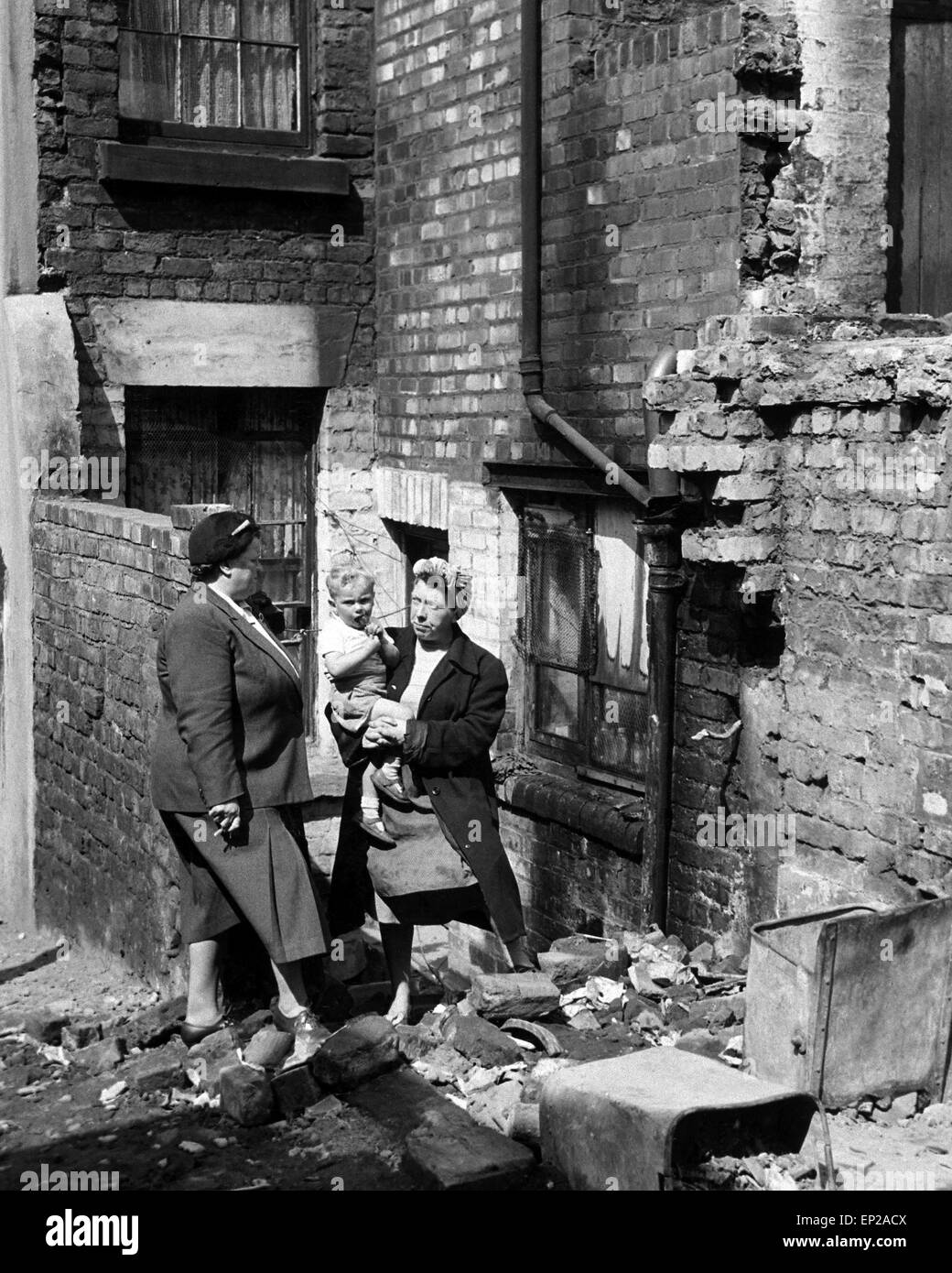 MP Bessie Braddock treffen Bewohner in einem Liverpool Slum Gegend wohnen. Frau McGuiness und ihrem kleinen Sohn Peter, im Alter von 2, musste klettern über Abriss Schutt auf die Rückseite ihres Hauses, Liverpool, Merseyside verlassen. 12. Juli 1954 Stockfoto