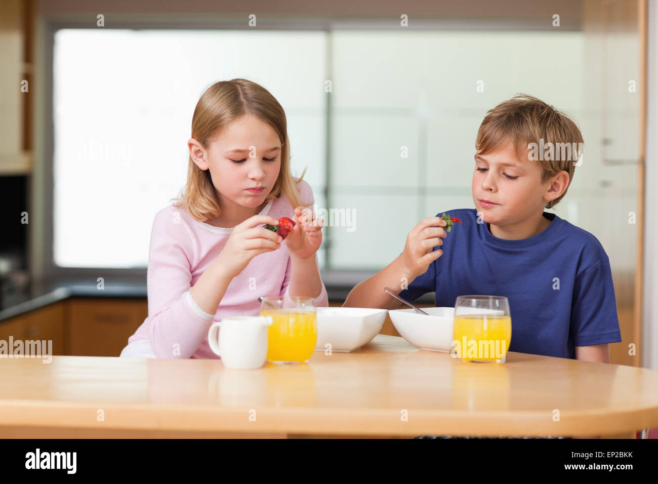 Niedliche Kinder essen Erdbeeren zum Frühstück Stockfoto