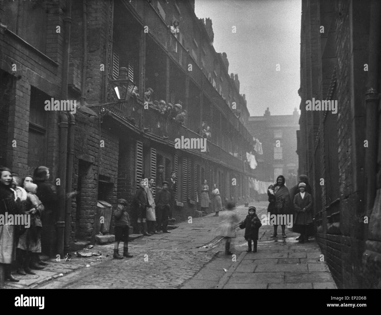 Menschen, die zwischen zwei Terrassen in einem Slum Gehäuse Fläche von Liverpool stehen. 2. März 1933. Stockfoto