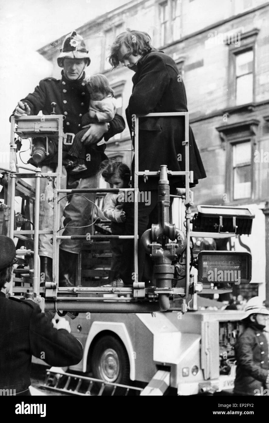 Feuer bei Maryhill Road Glasgow. Feuer bricht in einen unbesetzten Möbelgeschäft Verbreitung entlang der Ladenzeile und fangen einige Familien in ihren Häusern oben. Fünfzig Familien wurden obdachlos, und eine Frau und ein Feuer Offizier ums Leben. Samstag, 18. November 1972. Das Bild zeigt John Mathieson, die zwei Kinder aus dem Feuer gerettet. Isobel ab 3 Jahren von einem Feuerwehrmann gehalten wird und Robert im Alter von 4 hält auf Mathiesons Bein. Stockfoto