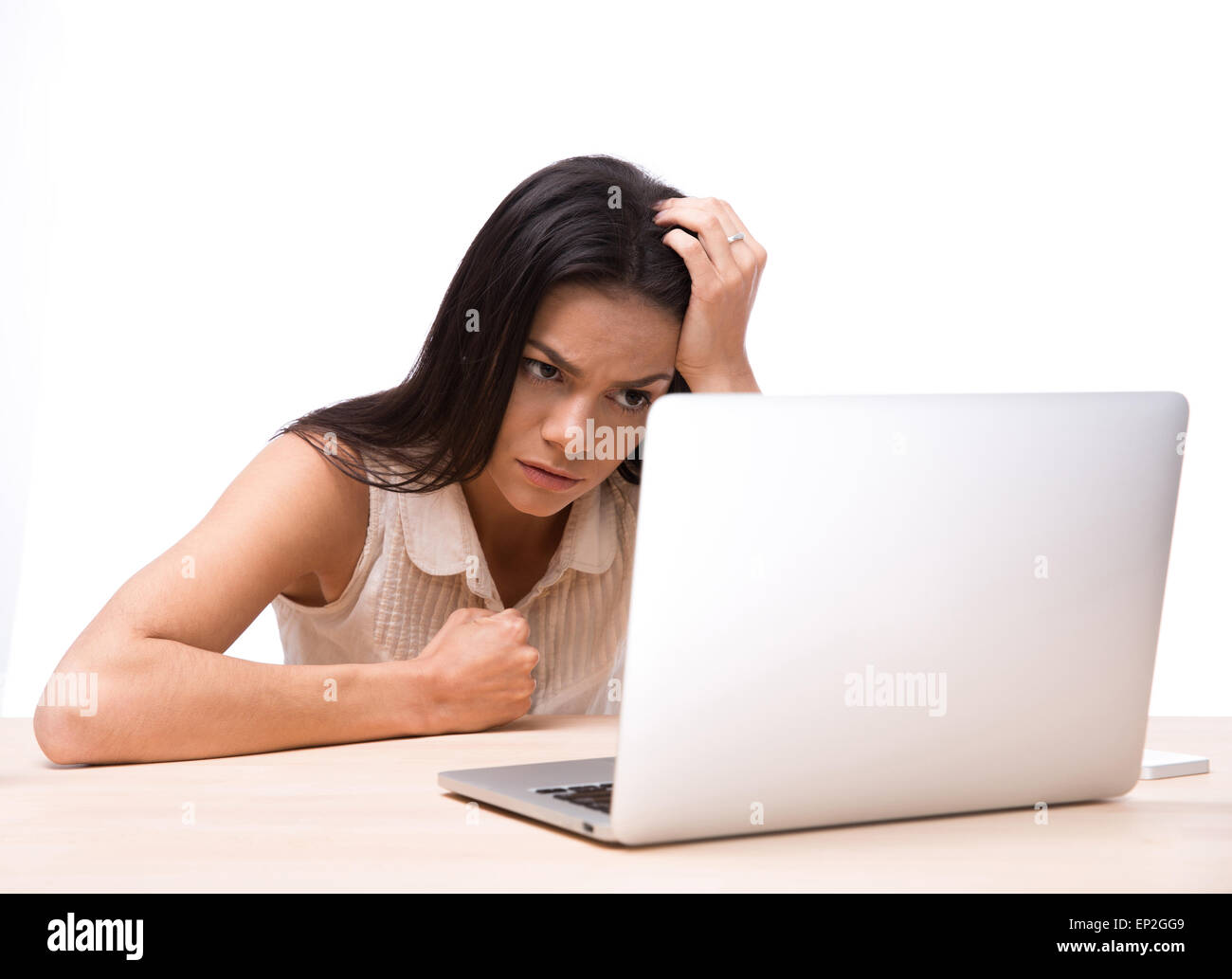 Böse Frau sitzt am Tisch mit Laptop auf weißem Hintergrund. Laptop-Bildschirm betrachten Stockfoto