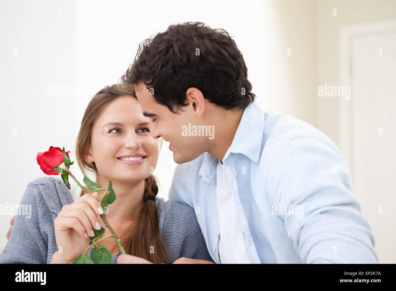 Mann, einer Frau eine Rose anzubieten, und genießen Sie im Innenbereich Stockfoto