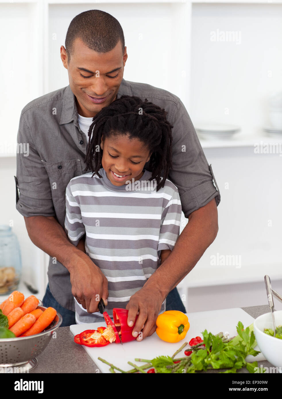 Aufmerksamen Vater helfen, sein Sohn Gemüse Schneiden Stockfoto