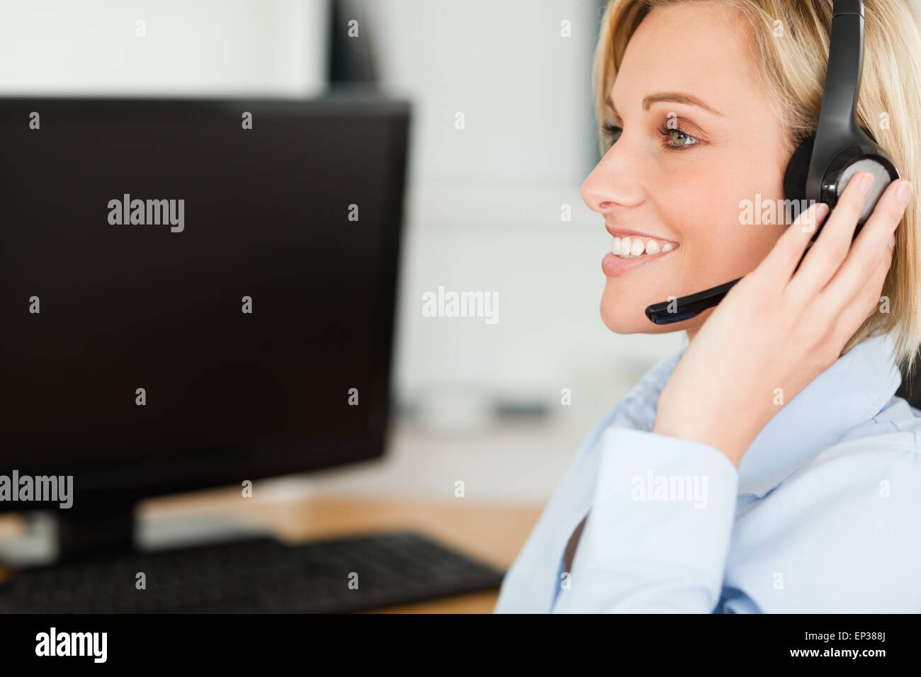 Porträt von lächelnden blonden Geschäftsfrau mit Kopfhörer arbeiten mit Computern, die auf der Suche an anderer Stelle Stockfoto