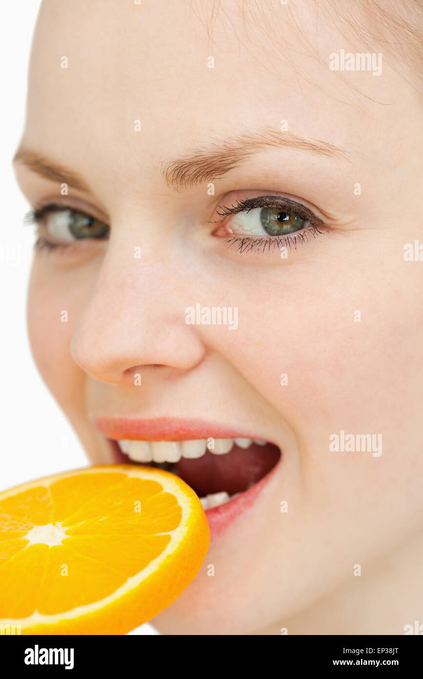 Nahaufnahme einer Frau eine Orangenscheibe in den Mund legen Stockfoto