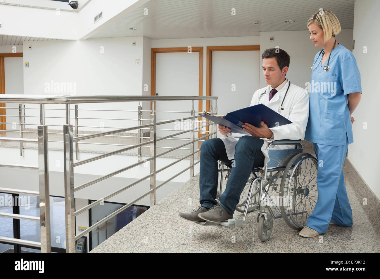 Arzt, sitzen im Rollstuhl, die Prüfung von Notizen mit Krankenschwester Stockfoto