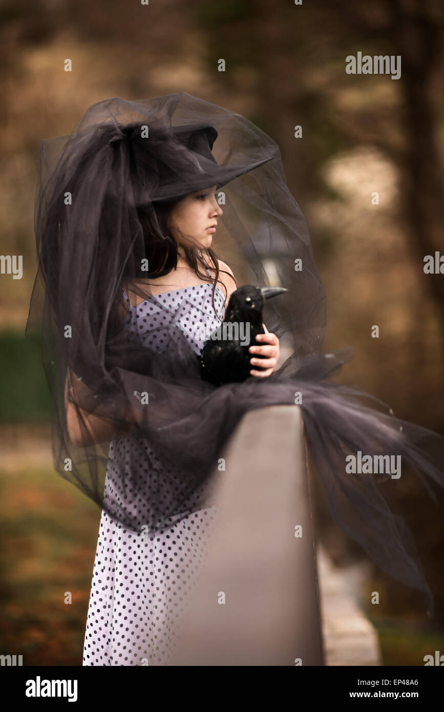 Mädchen in einen schwarzen Schleier halten einen gefüllten schwarzen Vogel Stockfoto